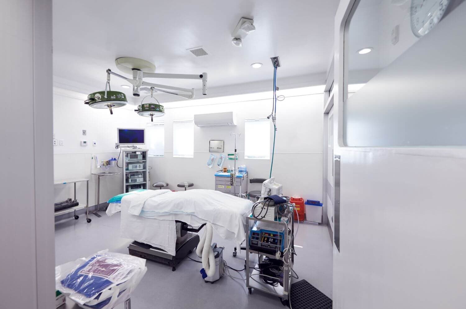 Modern operating room setup featuring surgical equipment, lighting, and a patient bed prepared for a medical procedure.
