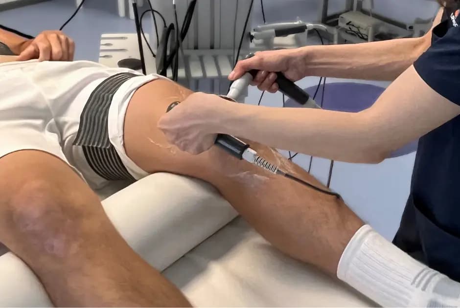 Therapist using a radiofrequency applicator on a patient's leg during a clinical session.
