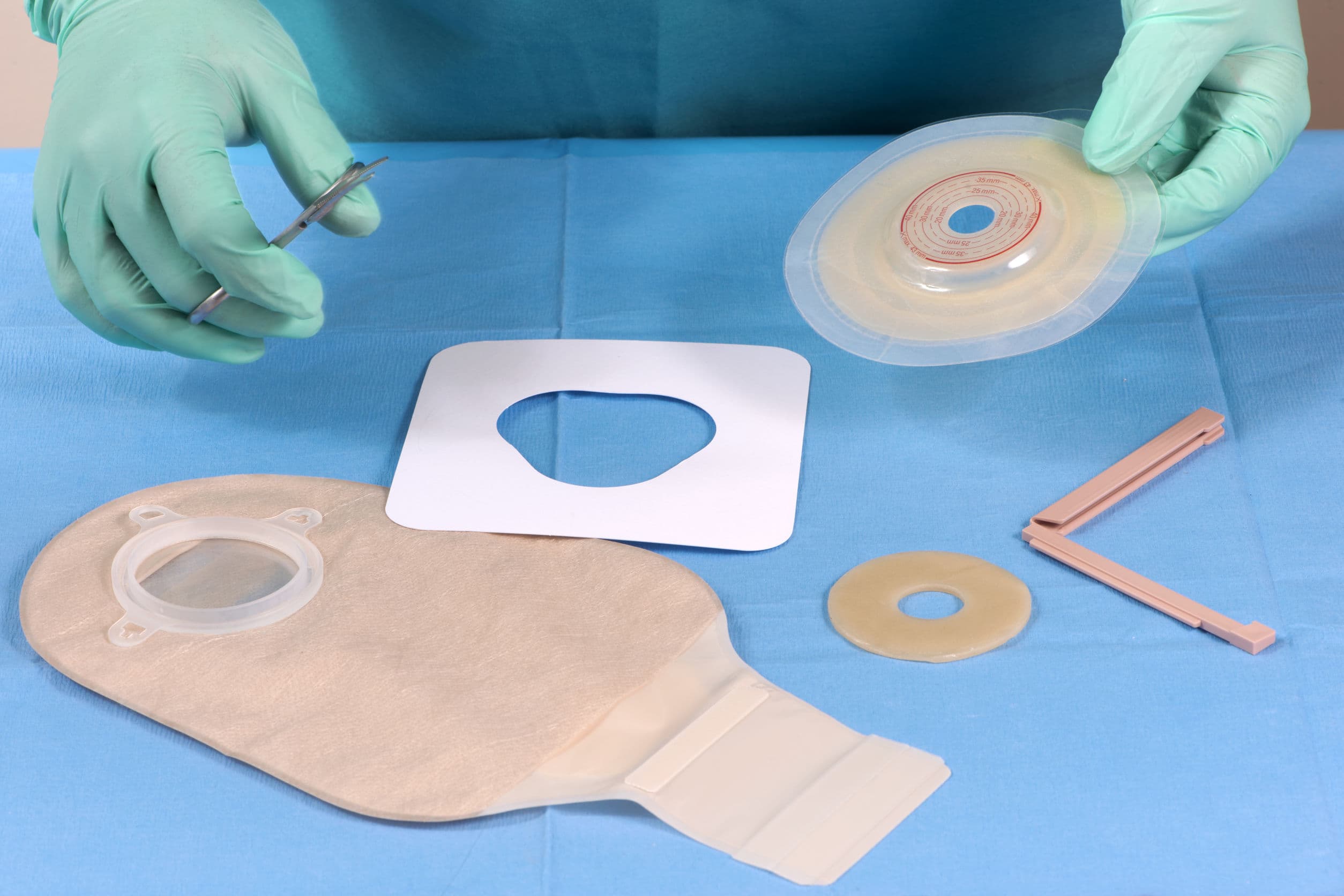 Colostomy kit components including bag, skin barrier, and accessories laid out for preparation.