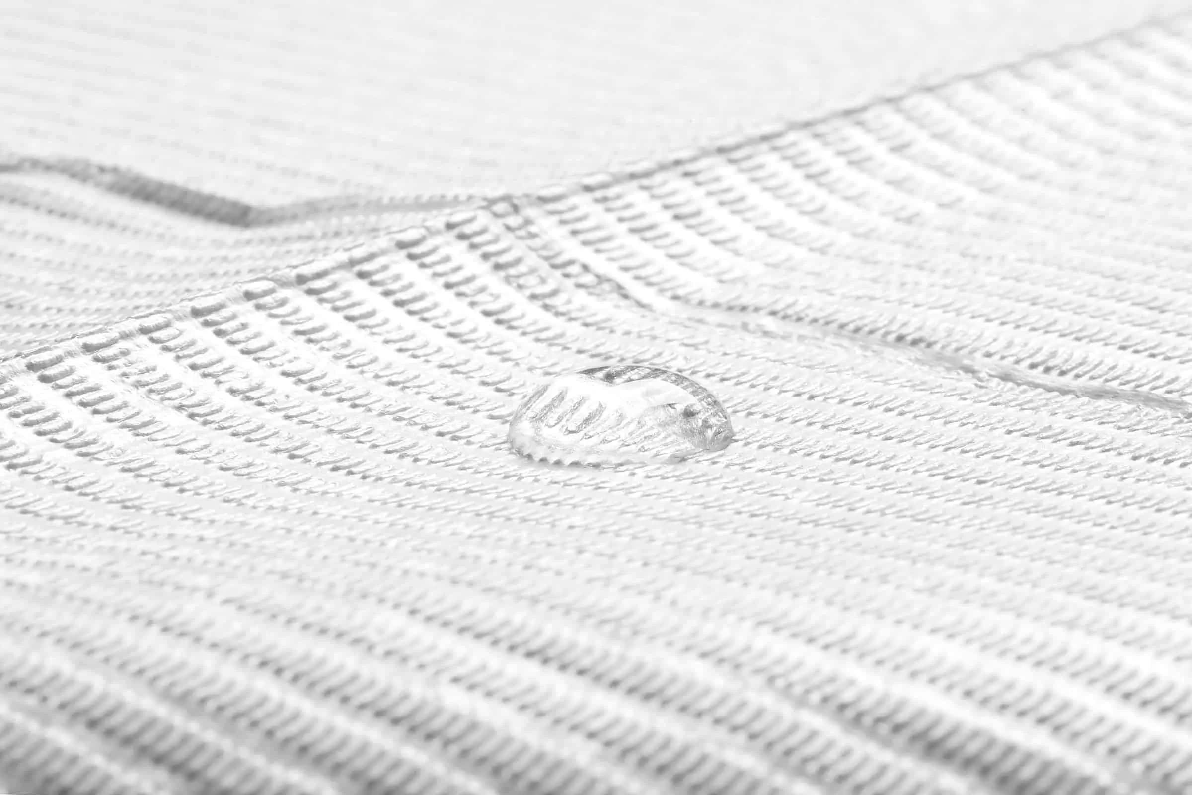 Close-up macro shot of a water droplet on medical fabric, demonstrating the material's absorbent properties.