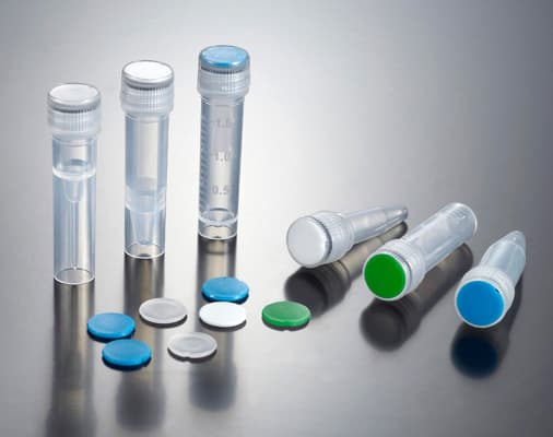A collection of clear laboratory microtubes with screw caps and various colored inserts arranged on a reflective gray studio surface.