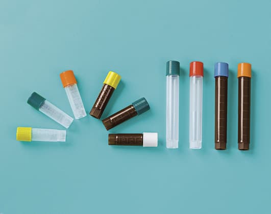 A collection of various laboratory cryotubes with different colored caps arranged on a solid light blue background.