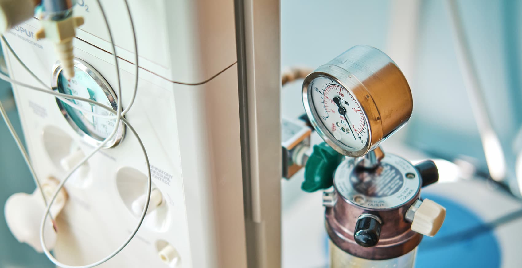 Close-up view of a medical suction regulator and pressure gauge attached to a hospital wall-mounted gas supply unit.