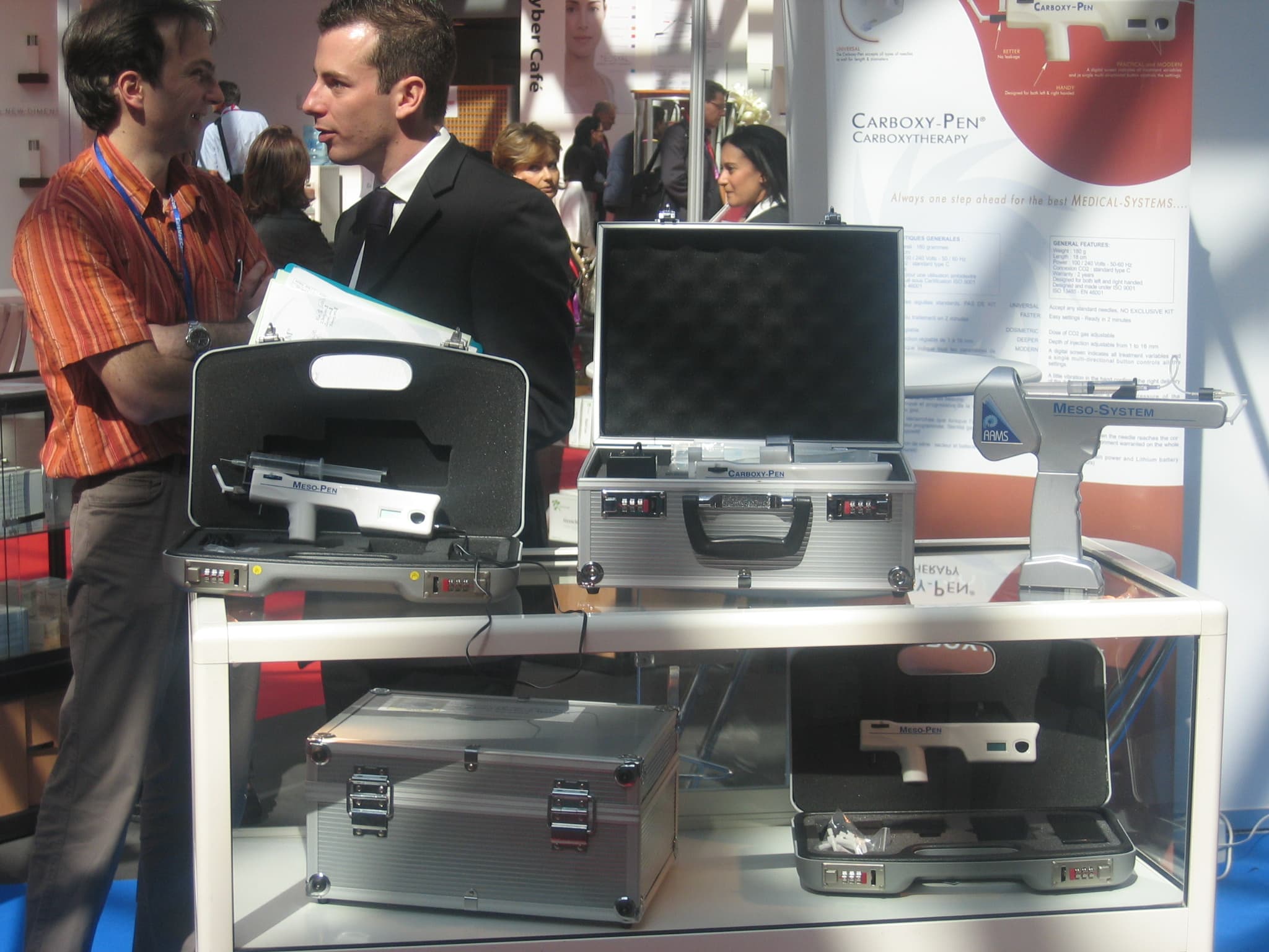 A historical trade show booth featuring AAMS founders and a display of multiple medical device kits and carrying cases.
