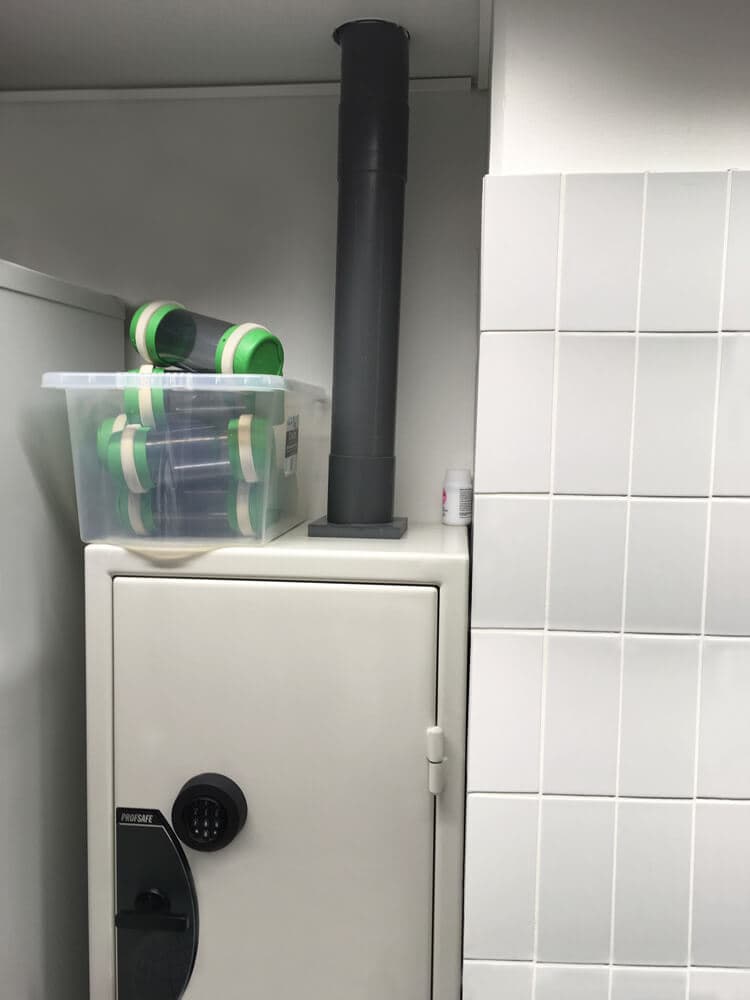 Pneumatic tube system terminal installed above a secure safe for cash transport and storage.