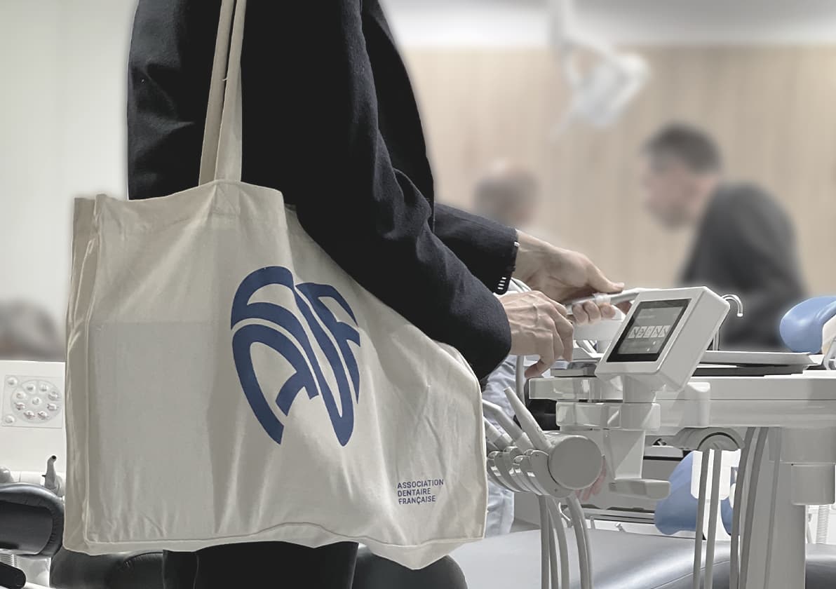 Dental professional holding an ADF branded tote bag in a clinic setting with dental equipment visible.