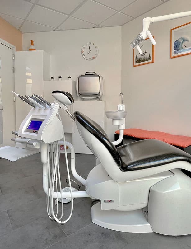 Modern dental operatory featuring a patient chair, integrated delivery unit, and overhead lighting system.