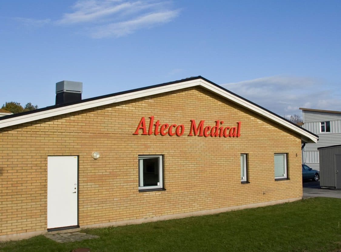 Exterior view of a single-story brick building with the Alteco Medical company name mounted on the front facade.