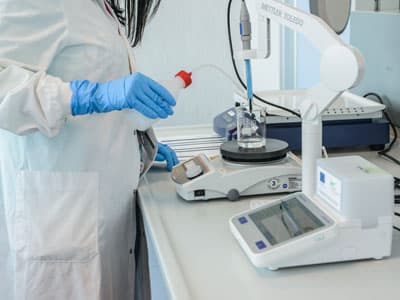 Researcher in a laboratory setting using a precision balance and analytical equipment for pharmaceutical development.