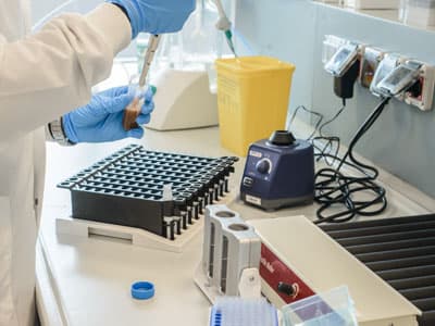 Laboratory workspace featuring a multi-well plate, vortex mixer, and various chemical analysis tools for research.