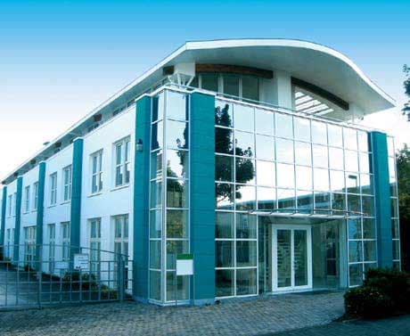 Modern multi-story corporate headquarters building with glass facade and teal architectural accents, representing the company's physical facility.