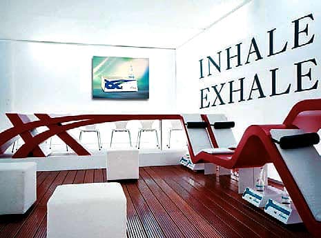 Wellness lounge area featuring ergonomic red seating, wooden flooring, and wall signage promoting breathing health and wellness.