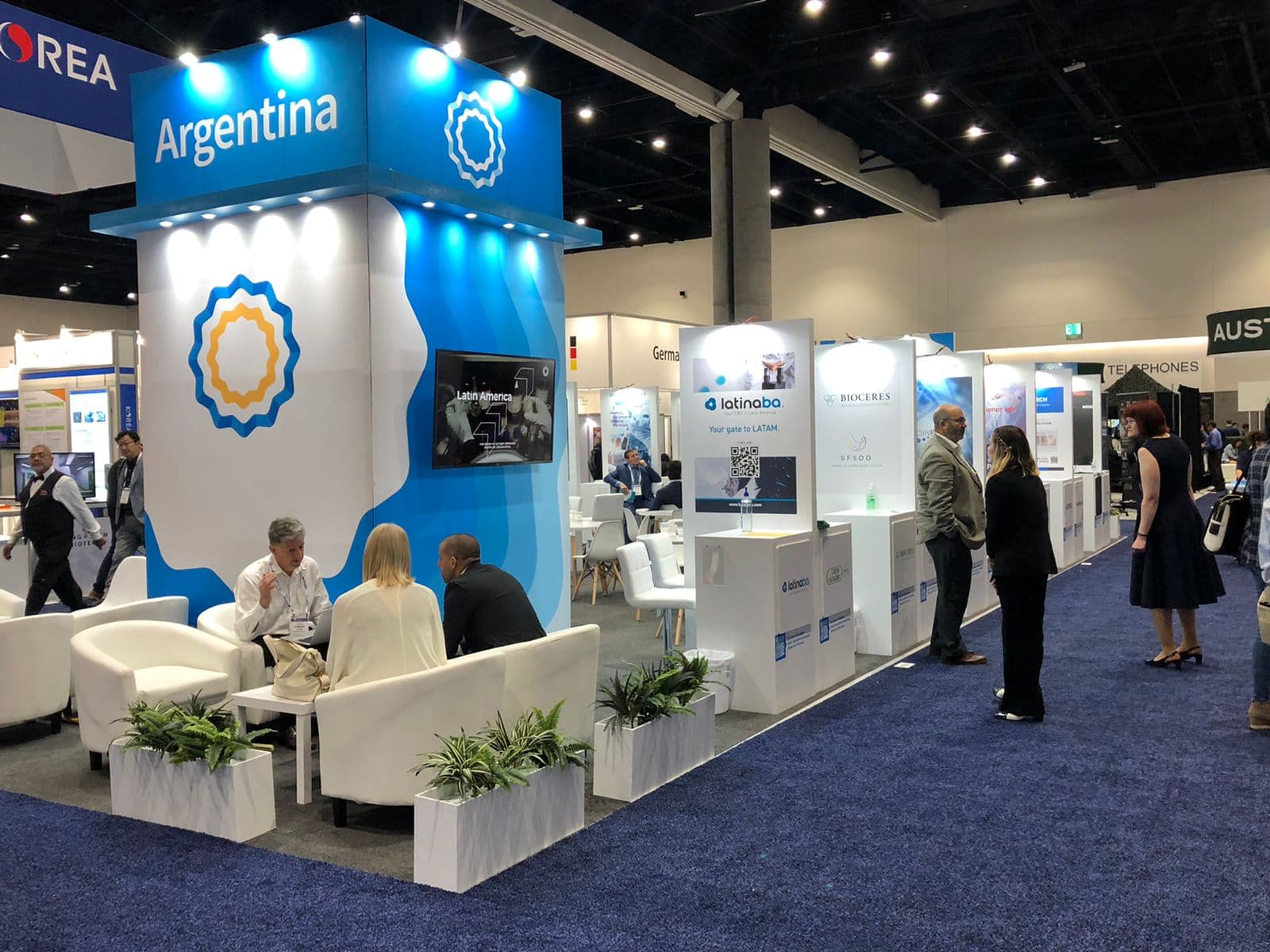 Company representatives engaging with visitors at a branded exhibition booth during an international biotechnology convention.