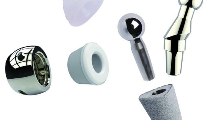 A collection of various orthopedic implant components, including femoral heads and stems, displayed as a product range.