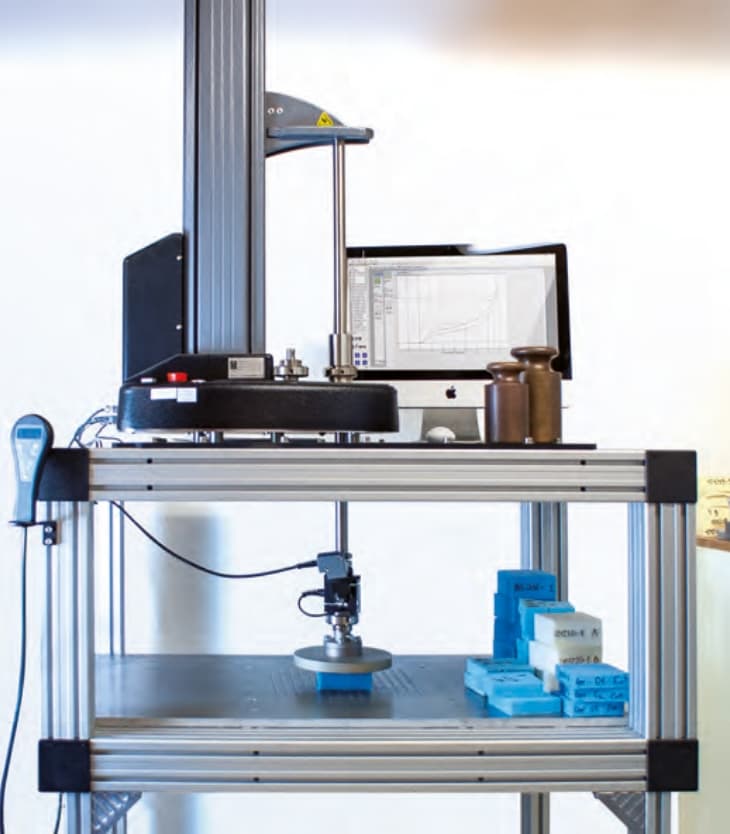 Laboratory testing equipment performing stress and pressure analysis on medical foam samples.