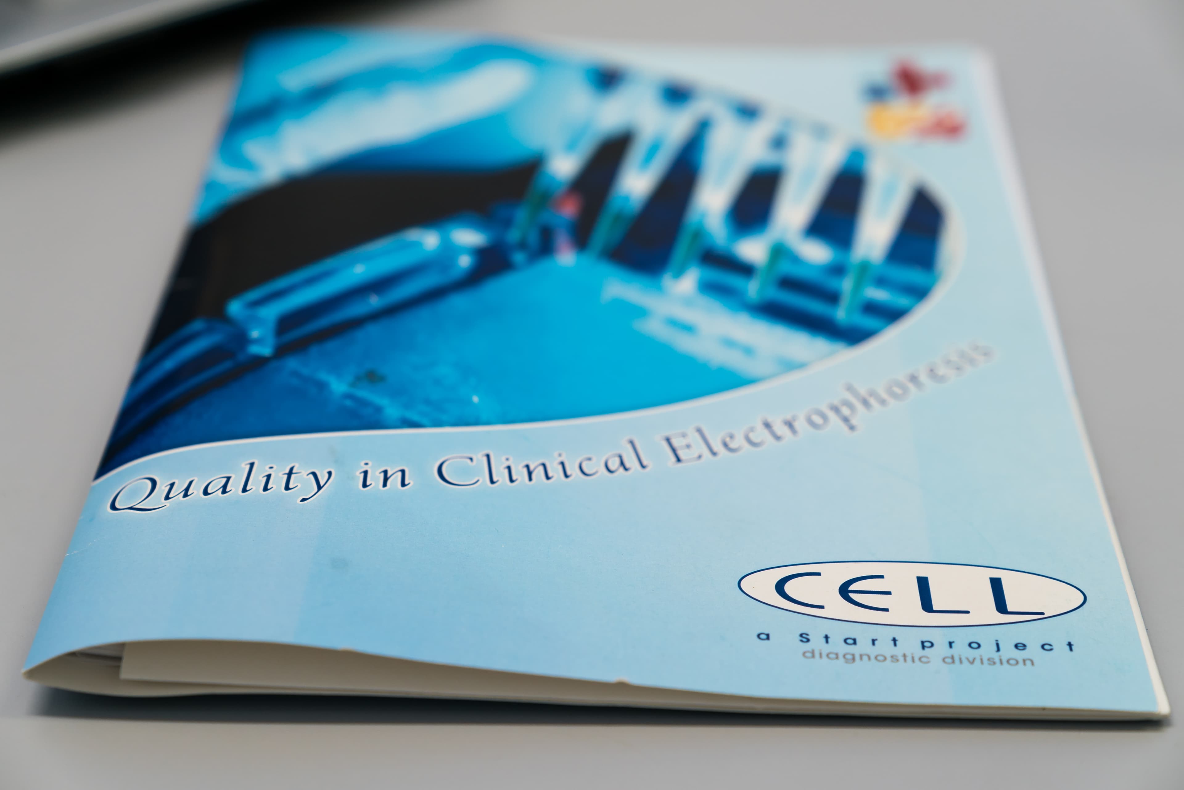 A printed marketing brochure for Cell Start Project featuring a blue-toned graphic of laboratory electrophoresis equipment on the cover.