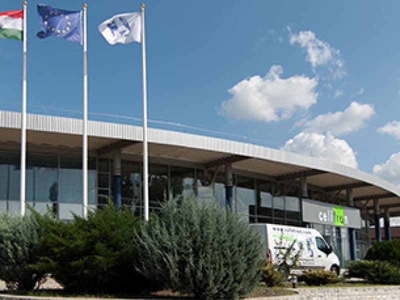 Wide shot of the Celitron facility exterior with national and European Union flags flying.