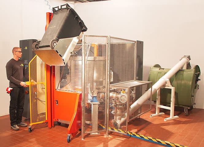 Operator using an integrated medical waste sterilizer and shredder unit in a professional clinical environment.