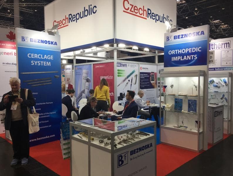 Trade show booth showcasing a range of orthopedic implants and medical devices in display cases.