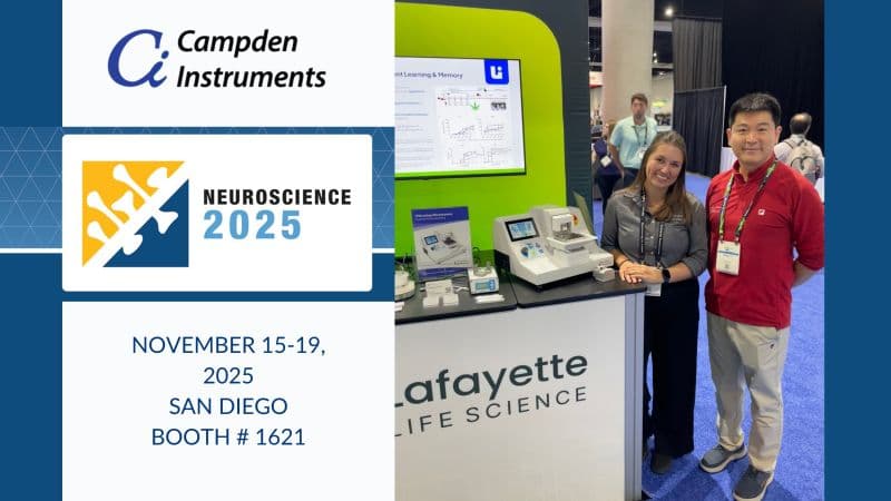 Company representatives at a trade show booth with medical equipment and event signage.