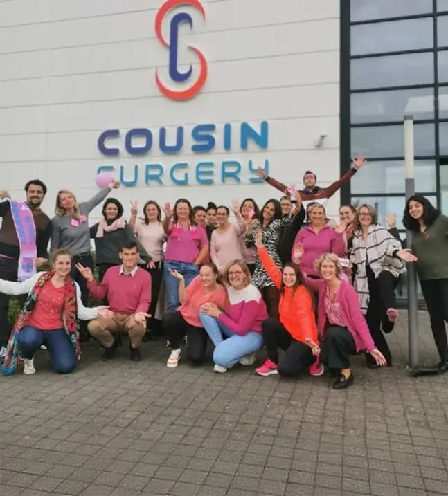 Group photo of the Cousin Surgery team celebrating in front of the company headquarters building.