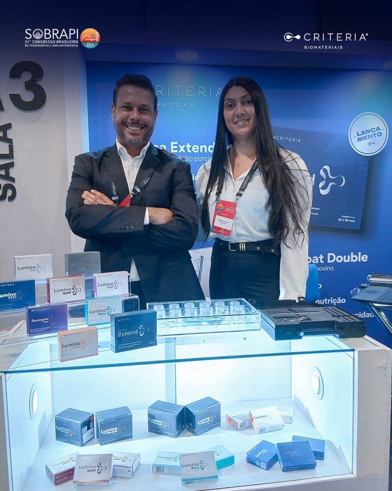 Company representatives standing at a trade show booth displaying a range of biomaterial product packaging and samples.