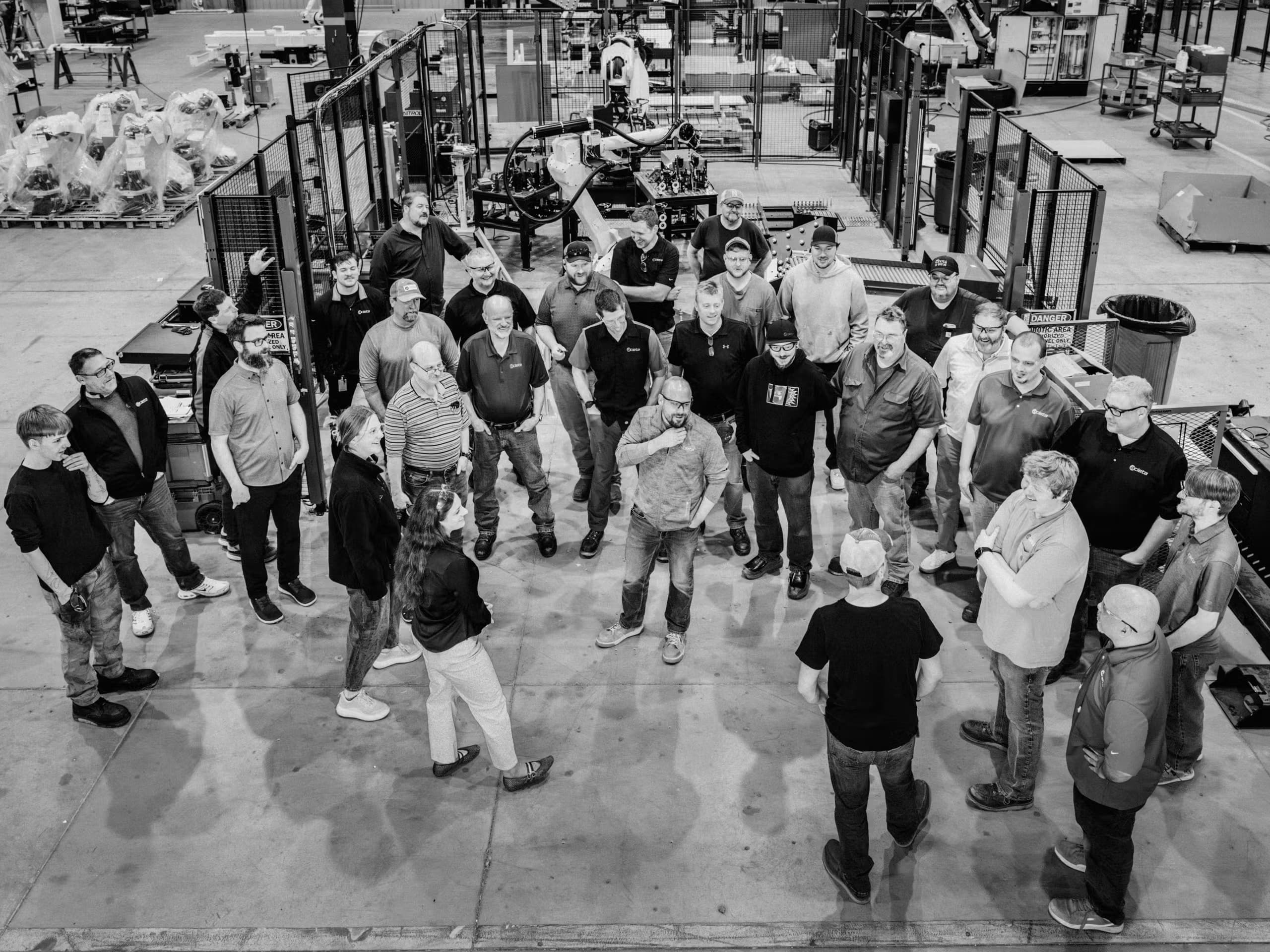 Large group of staff members gathered on the factory floor for a company team photo.