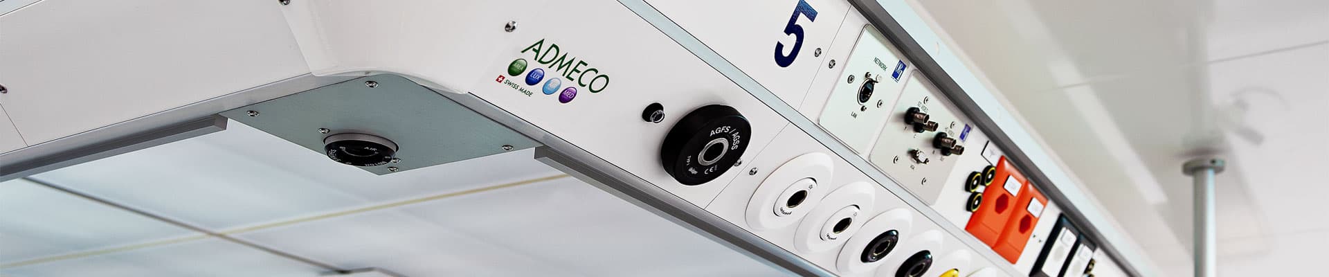 Close-up view of a ceiling-mounted medical supply bridge featuring gas outlets, electrical sockets, and the ADMECO brand logo.